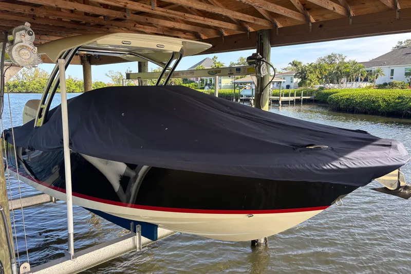 Slide: The Image of 2023 Chris-Craft Calypso 24 boat covered and docked under a wooden shelter. - 18