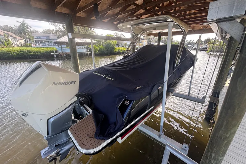 Slide: The Image of 2023 Chris-Craft Calypso 24 boat with Mercury engine, covered and docked on a lift. - 20