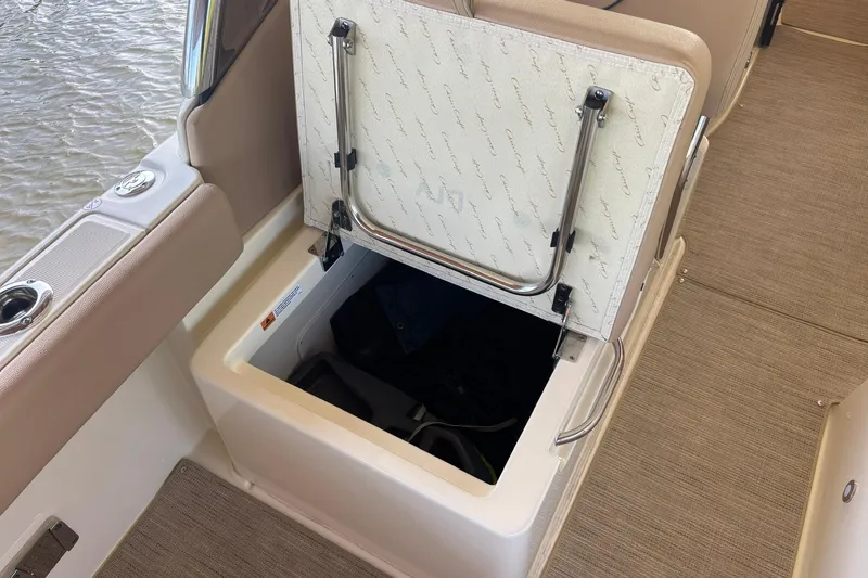 Slide: The Image of 2023 Chris-Craft Calypso 24 boat storage compartment with open hatch, beige interior. - 23