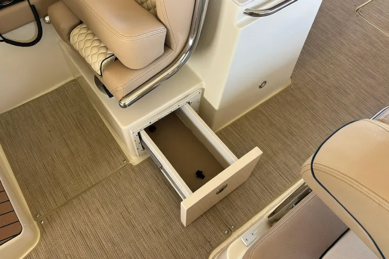 Slide: The Image of 2023 Chris-Craft Calypso 24 interior with open storage drawer and beige seating. - 24