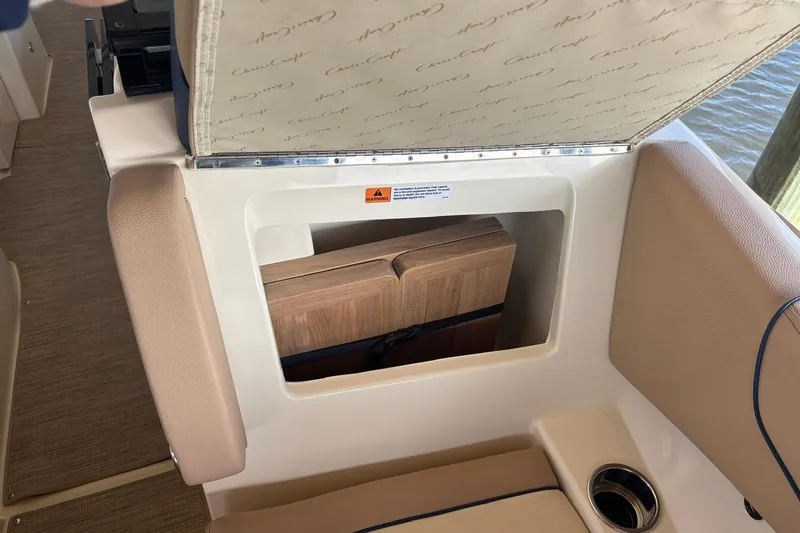 Slide: The Image of 2023 Chris-Craft Calypso 24 boat storage compartment with cushioned seating and wooden interior. - 27