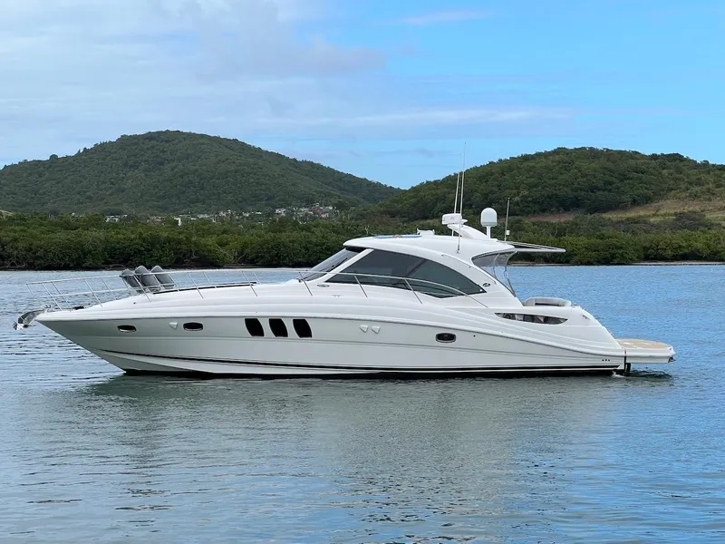 The Image of 2006 Sea Ray 48 Sundancer yacht on calm water with green hills. - 0