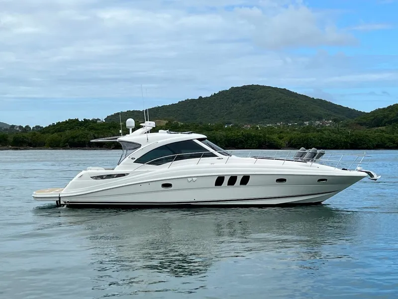 Slide: The Image of 2006 Sea Ray 48 Sundancer on calm water with wooded hill backdrop. - 15
