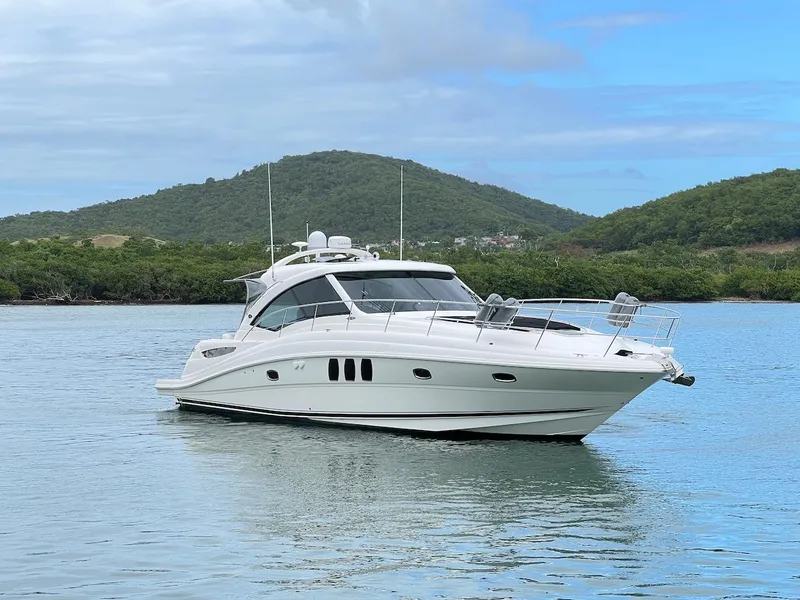 Slide: The Image of 2006 Sea Ray 48 Sundancer yacht on calm water with green hills. - 18