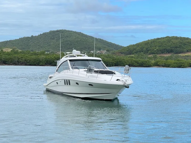 Slide: The Image of 2006 Sea Ray 48 Sundancer on calm water with green hills. - 19