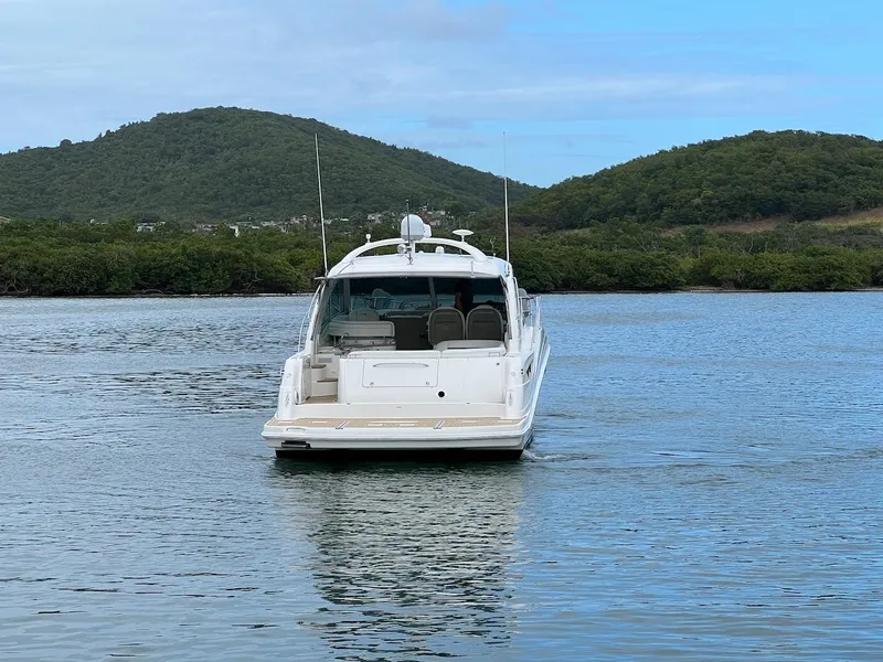 Slide: The Image of 2006 Sea Ray 48 Sundancer on calm water with green hills. - 22