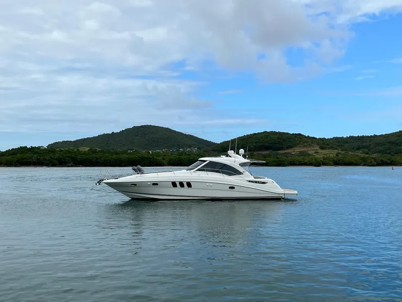 Slide: The Image of 2006 Sea Ray 48 Sundancer on calm water with green hills. - 3