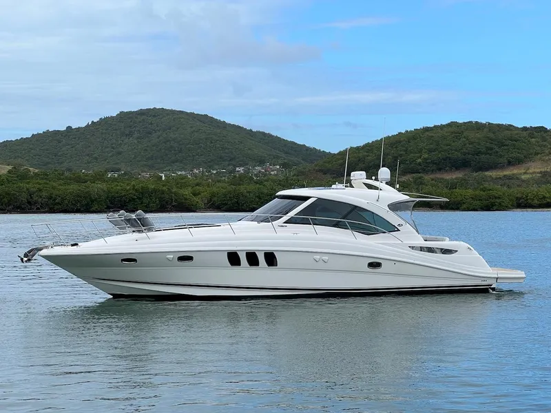 Slide: The Image of 2006 Sea Ray 48 Sundancer yacht on calm water with green hills. - 6