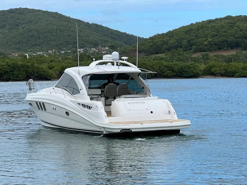 Slide: The Image of 2006 Sea Ray 48 Sundancer on calm water with green hills. - 9
