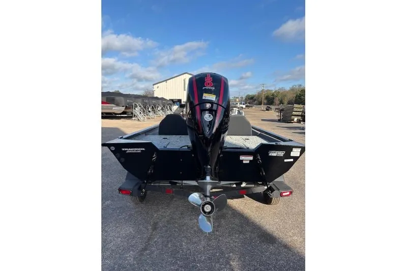 Slide: The Image of 2026 Tracker Pro Team 195 boat with outboard motor, parked outdoors under blue sky. - 5