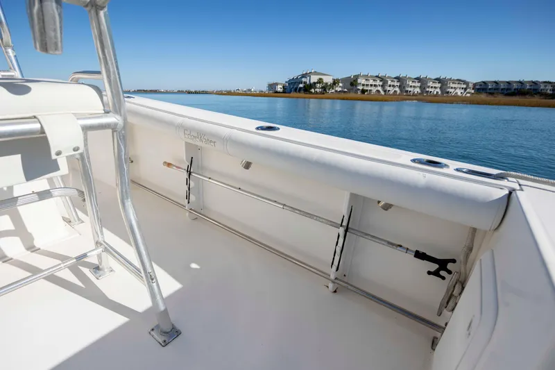 Slide: The Image of 2006 Edgewater 228CC boat interior with rod holders, near waterfront homes. - 11