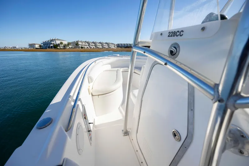 Slide: The Image of 2006 Edgewater 228CC boat on calm water with coastal buildings in background. - 17