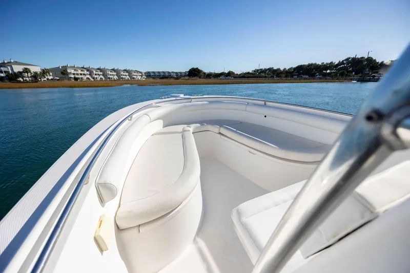 Slide: The Image of 2006 Edgewater 228CC boat interior with white seating, on calm water, under clear blue sky. - 18