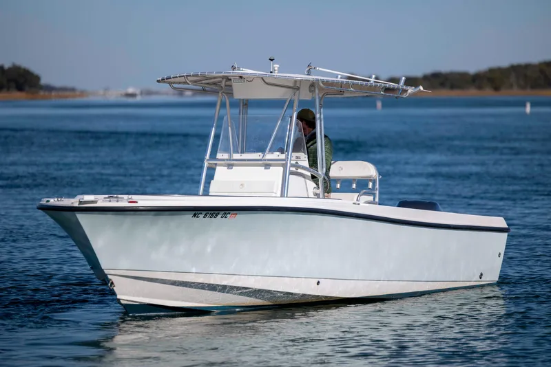 Slide: The Image of 2006 Edgewater 228CC boat on calm water with a person at the helm. - 2