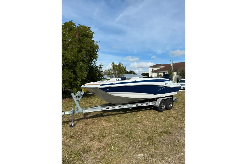 Slide: The Image of 2026 Crownline Eclipse E210 XS boat on trailer, parked on grass under blue sky. - 18