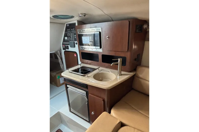 Slide: The Image of 2026 Crownline 280 CRX boat interior with kitchenette, featuring sink, stove, and microwave. - 15