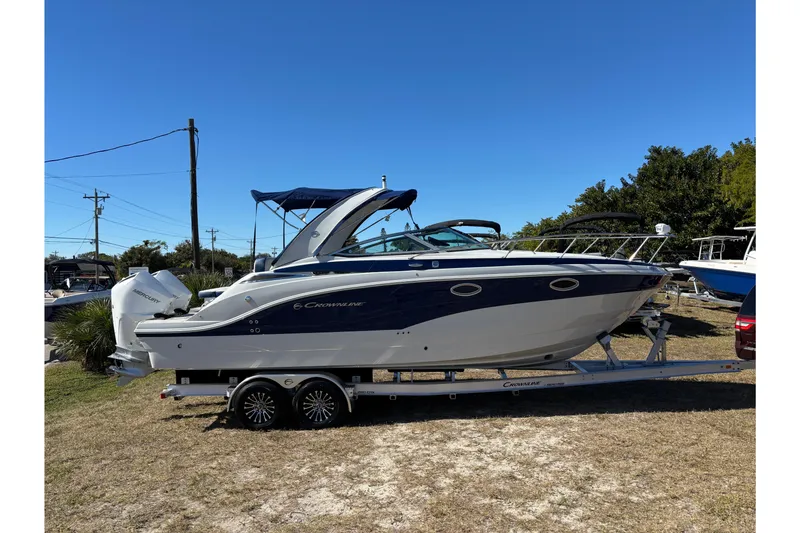 Slide: The Image of 2026 Crownline 280 CRX boat on trailer, parked outdoors under clear blue sky. - 19