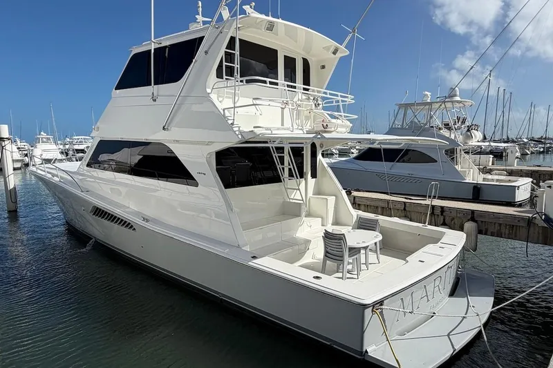 Slide: The Image of 1999 Viking 58 Convertible yacht docked at marina, featuring spacious deck and sleek design. - 2