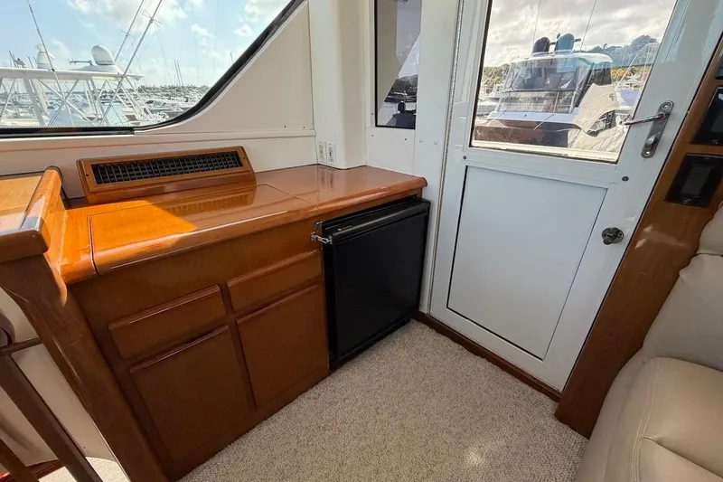 Slide: The Image of Interior of 1999 Viking 58 Convertible yacht with wooden cabinetry and small refrigerator. - 28