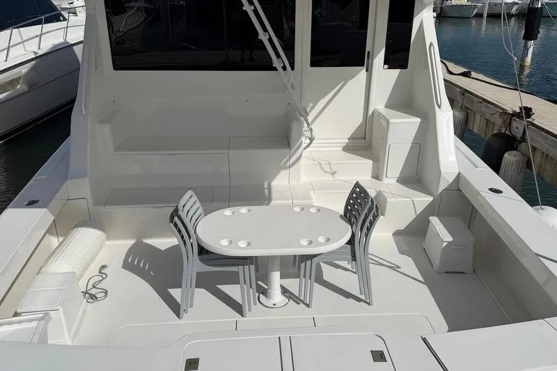 Slide: The Image of 1999 Viking 58 Convertible yacht deck with seating and table, docked at marina. - 3