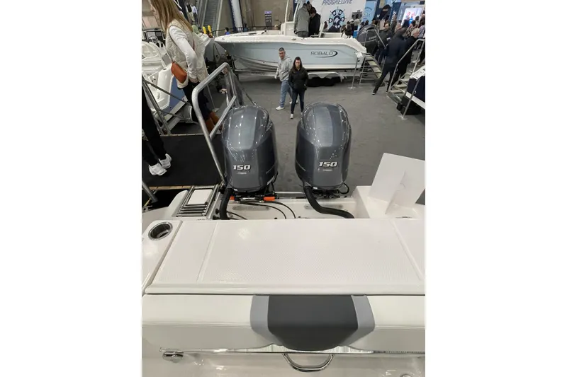 Slide: The Image of 2023 Robalo R250 Center Console with dual 150 horsepower engines at a boat show. - 2
