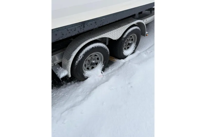 Slide: The Image of 2023 Robalo R250 Center Console trailer wheels covered in snow. - 23