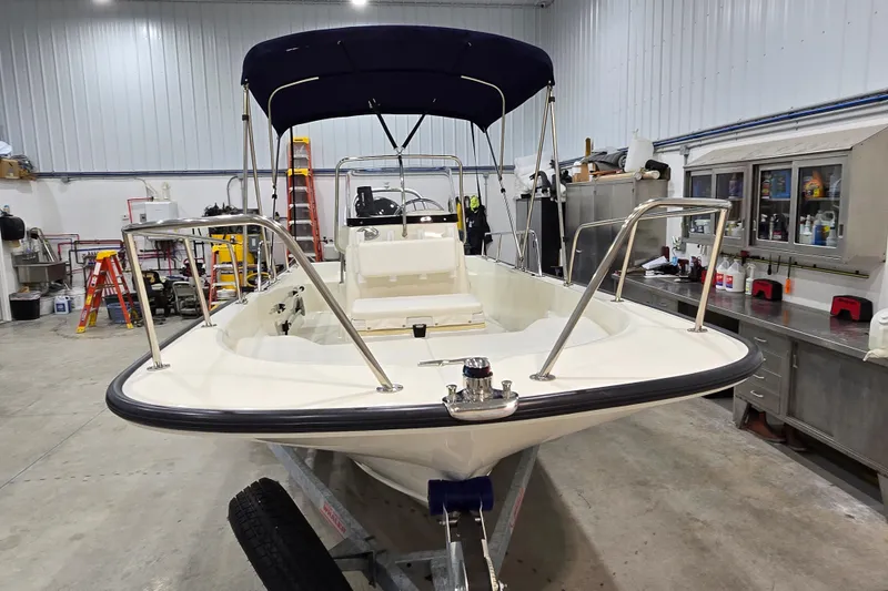 Slide: The Image of 2014 Boston Whaler 170 Montauk boat in a workshop, featuring a sleek design and canopy. - 8
