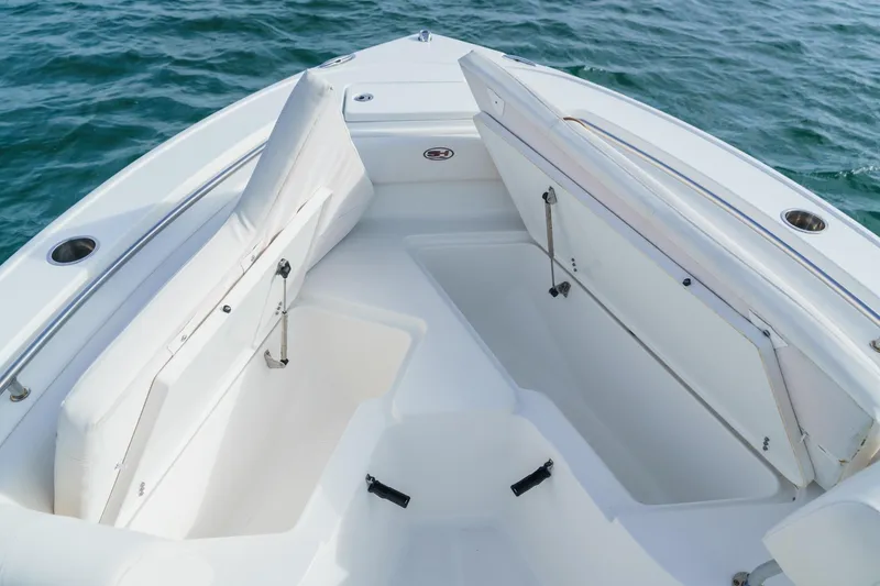 Slide: The Image of 2022 Sea Hunt Ultra 219 boat interior with open storage compartments on calm water. - 11