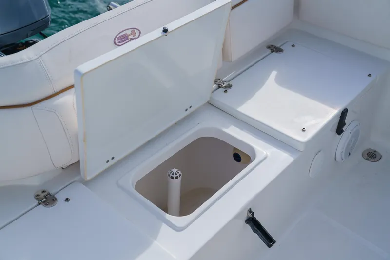Slide: The Image of 2022 Sea Hunt Ultra 219 boat storage compartment with open lid, showcasing interior features. - 17