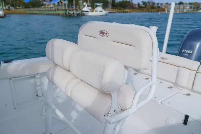 Slide: The Image of 2022 Sea Hunt Ultra 219 boat with cushioned seating, docked by the water. - 20