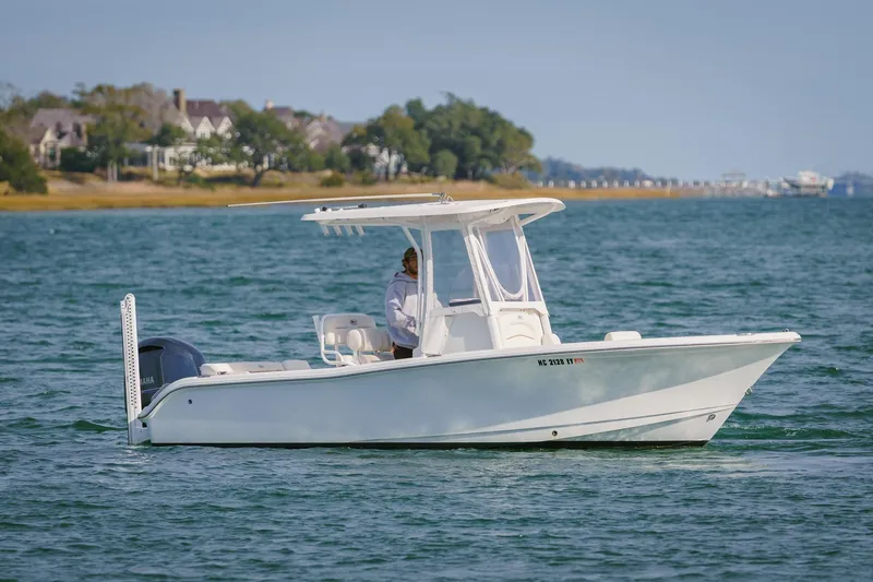 Slide: The Image of 2022 Sea Hunt Ultra 219 boat cruising on a calm lake with scenic shoreline. - 6