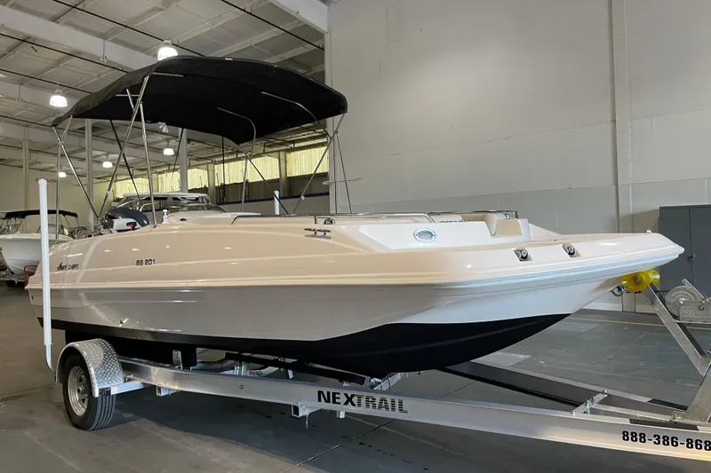 The Image of 2023 Hurricane SunDeck Sport 201 OB boat on trailer, parked outside a warehouse. - 1