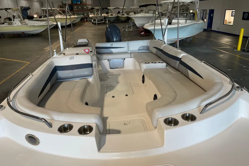 Slide: The Image of 2023 Hurricane SunDeck Sport 201 OB boat with canopy, docked near a warehouse. - 6