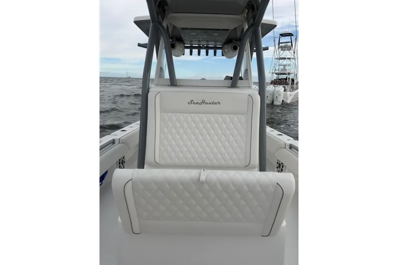 Slide: The Image of 2024 SeaHunter 28 Floridian boat interior with white quilted seating on the water. - 16