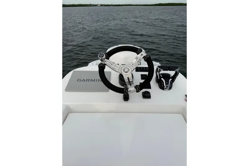 Slide: The Image of 2024 SeaHunter 28 Floridian helm with Garmin navigation, steering wheel, and throttle controls on open water. - 47