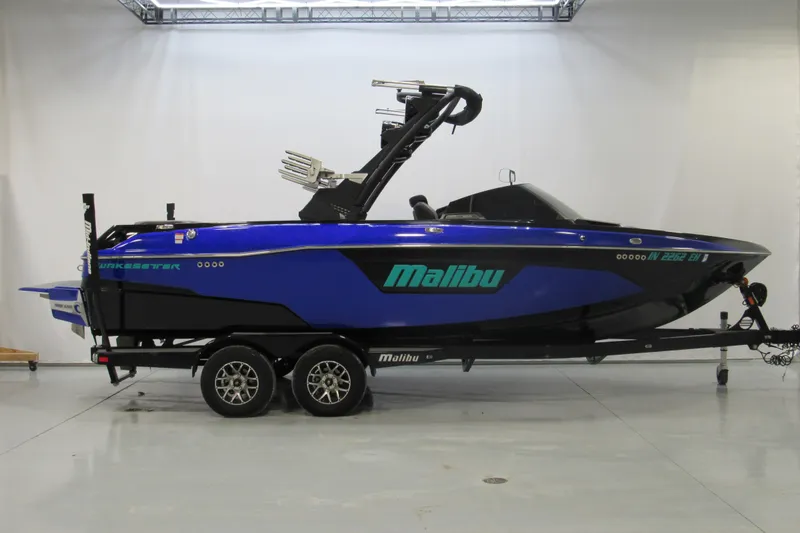 The Image of 2021 Malibu Wakesetter 23 LSV boat on trailer, blue and black design. - 1