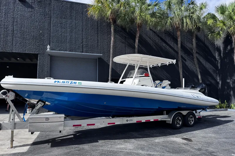 The Image of Blue and white Airship 330 boat on trailer, parked near palm trees, 2014 model. - 2