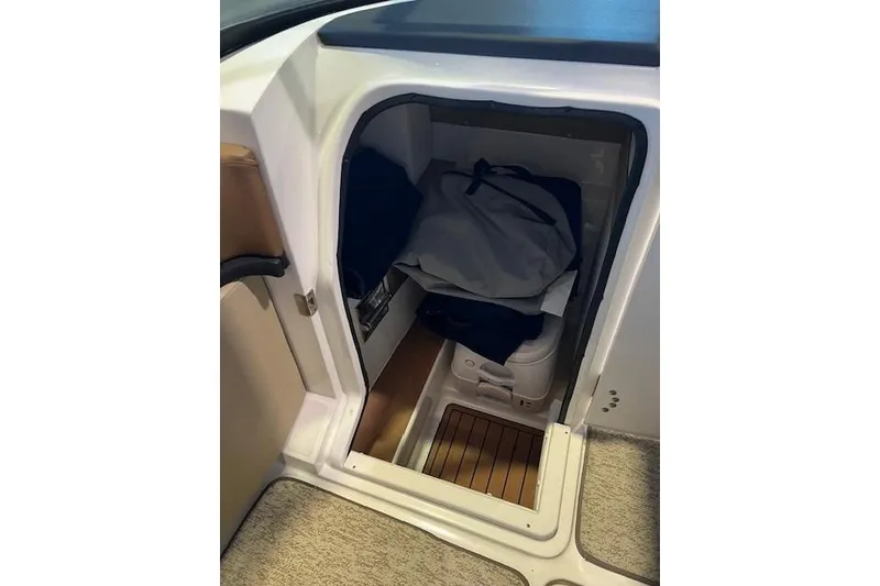 Slide: The Image of 2016 Sea Ray 250 SLX boat interior storage compartment with bags and wooden flooring. - 18