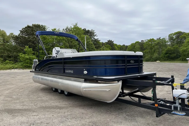 Slide: The Image of 2021 Harris FloteBote Sunliner 230 pontoon boat on trailer, parked outdoors. - 2