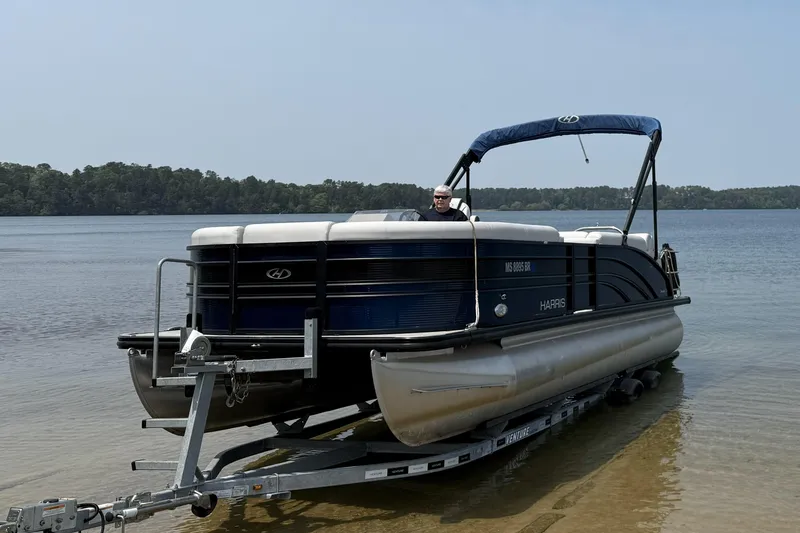 Slide: The Image of 2021 Harris FloteBote Sunliner 230 pontoon boat on trailer by a lake. - 3