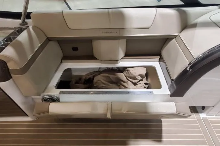 Slide: The Image of 2017 Formula 350 Crossover Bowrider interior with open storage compartment and beige seating. - 60