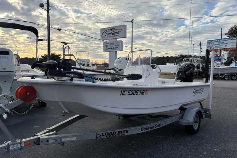 The Image of 2024 Coastal Skiff 171 boat on trailer at dealership, featuring Minn Kota motor. - 0