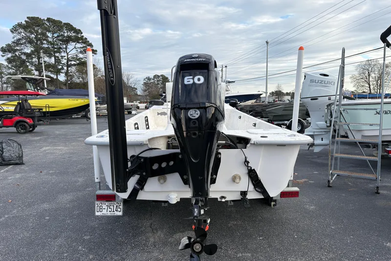 Slide: The Image of 2024 Coastal Skiff 171 with Mercury 60 outboard motor in a boatyard setting. - 2