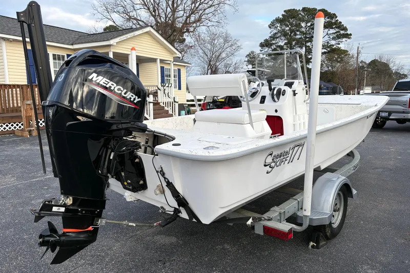 Slide: The Image of 2024 Coastal Skiff 171 boat on trailer with Mercury outboard motor, parked outdoors. - 4