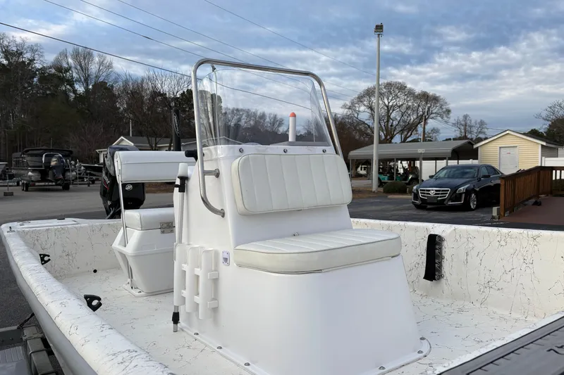 Slide: The Image of 2024 Coastal Skiff 171 boat with white seating, parked outdoors under a cloudy sky. - 7