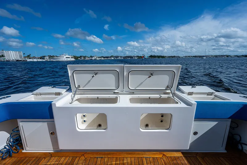 Slide: The Image of 2021 Gulf Crosser 52 boat with open storage compartments on deck, docked by the water. - 21