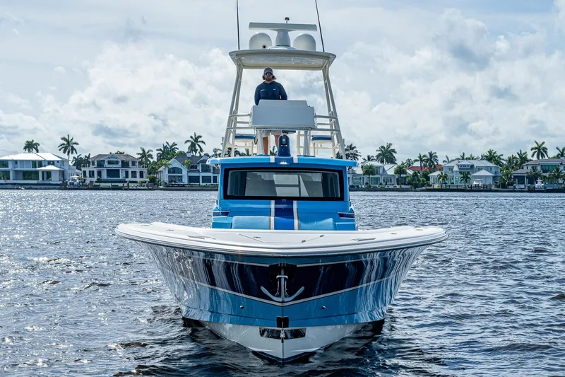 Slide: The Image of 2021 Gulf Crosser 52 boat on water with captain, waterfront homes in background. - 4
