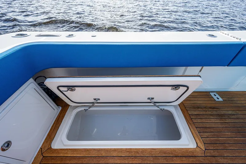 Slide: The Image of Open storage compartment on 2021 Gulf Crosser 52 boat with blue seating and wooden deck. - 41