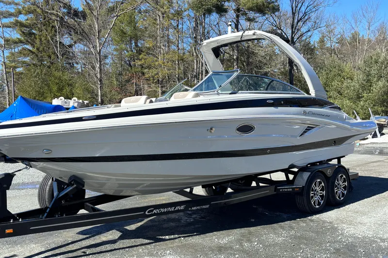 The Image of 2026 Crownline 278 SS boat on trailer, parked outdoors, surrounded by trees. - 0