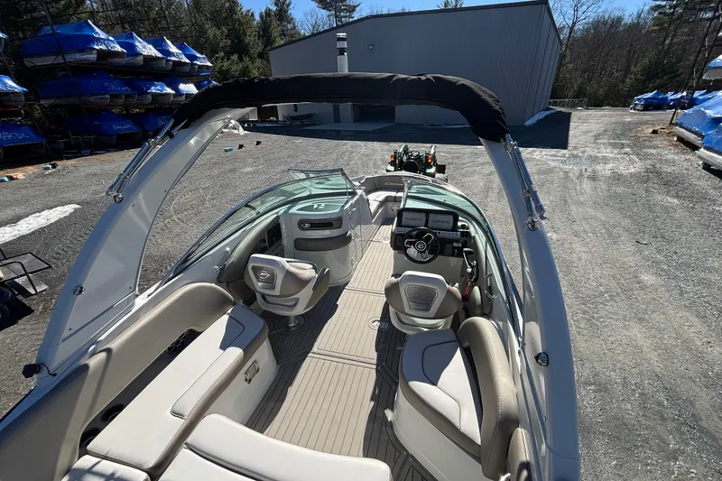 Slide: The Image of 2026 Crownline 278 SS boat interior with seating and dashboard, parked outdoors. - 12
